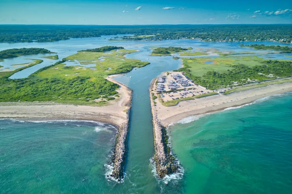 Aerial view of canal cut into beach in Charlestow, Rhode Island with boats parked in sand.